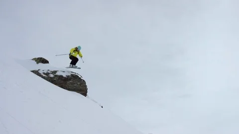 Elite skier jumping from rock while skiing down the snowy mountain slope Stock Footage 116743412