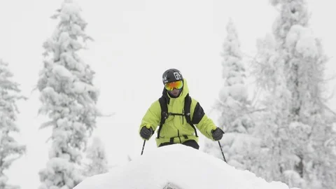 Elite skier jumping off of snowy ledge in woodsy slope Stock Footage 113234239