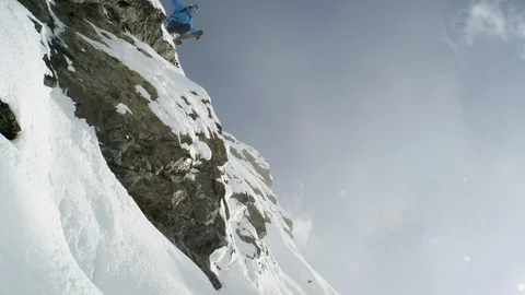 Elite skier jumping off snowy ledge on a remote mountain with lens flare Stock Footage 113242370