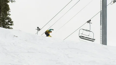 Elite skier jumping off of trail side jump and landing a 360 Stock Footage 113204316