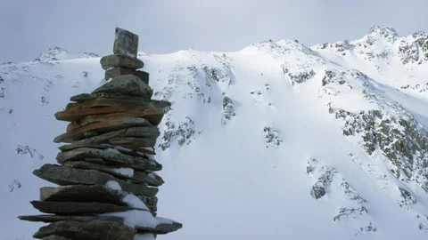 Elite skier making turns while skiing down the slope, stone stack in foreground Stock Footage 116741693