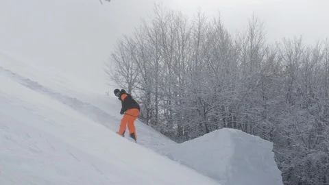 Elite skier performing a 180 spin off a trailside jump into fresh powder snow Stock Footage 113220355