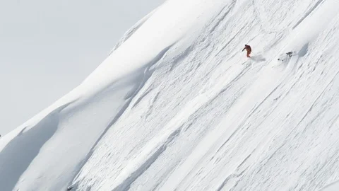 Elite skier skiing down steep face of a remote mountain Stock Footage 113216461