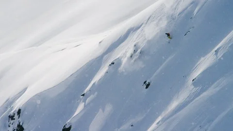 Elite skier speeding down a remote powder covered mountain slope Видео 113250476