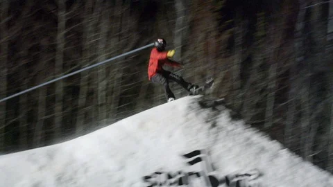 Elite snowboarder jumps and performs a Indy grab flip at night Video stock 116786552