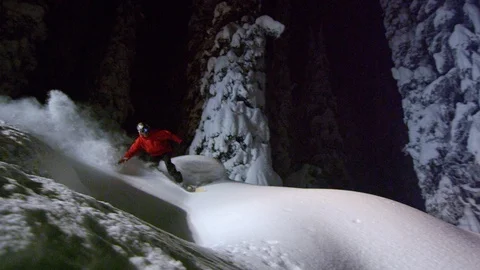 Elite snowboarder rolling through deep powder snow at night Stock Footage 116783323