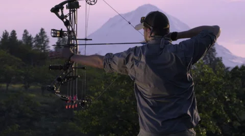 Elk Hunter Practices Using His Compound Bow At Sunset In The Mountains Stock Footage