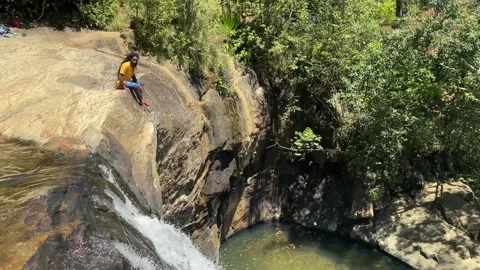 Ella, Sri Lanka - march 5th 2025: man sits by fall as water cascades into pool 스톡 동영상 307862464