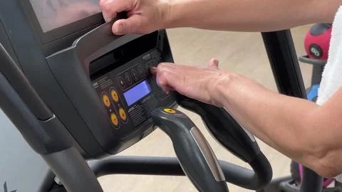 An elliptical cross-trainer is programmed for cardio training by a woman's .. Stock-Fotos