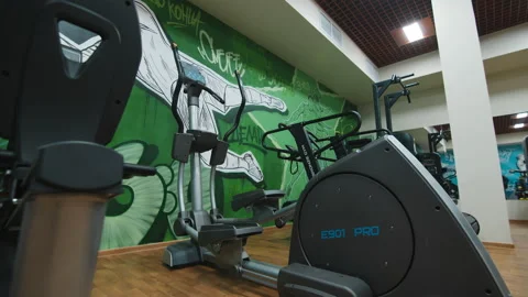 Elliptical training machine near green wall in light gym Stock Footage 172211026