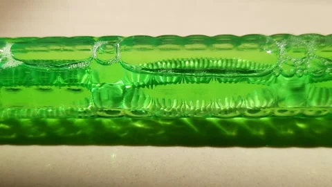 Elongated Air Bubbles and Flowing Liquid Patterns in Green Tube Stock Footage 344956860