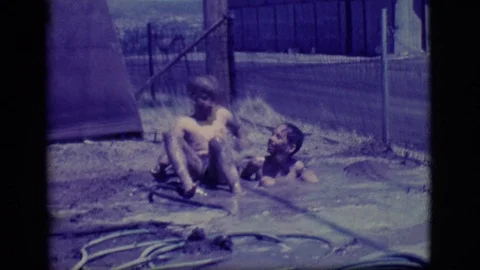 ELY NEVADA-1968: Two Boys Playing In A Tiny Muddy Pool They Made By Filling A Stock Footage 124749552