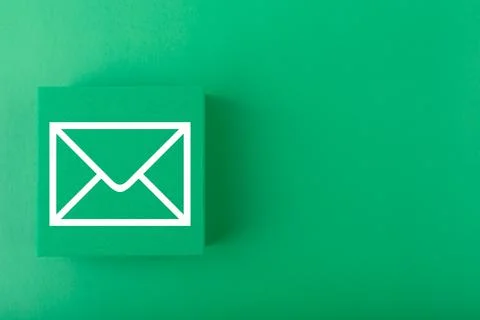 Email concept. Envelope drawn on toy square against dark green background with Stock Photos