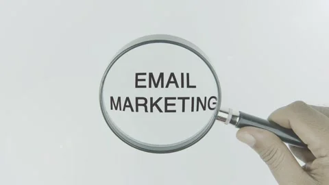 Email Marketing text or word highlighted by a magnifying glass in a hand Stock Footage 303616632