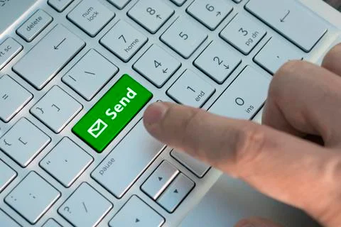 Email send button on the computer keyboard. A male finger presses a color but Stock Photos