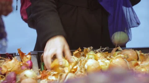 Emale hands choosing onion and putting in eco bag. Buying vegetables at store.  Видео 142157992