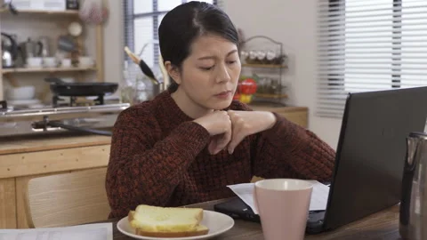 Emale sitting with computer having bread Stock Footage 133694311