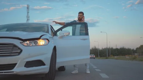Embarassed young man driver standing by modern white car crashed breakdown Stock Footage 114252146