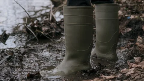 Embarking on a journey, exploring nature in my green rubber boots by a Stock Footage 305380708