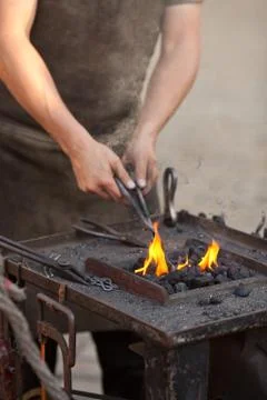 Embers, fire, smoke, tools and the hands of a blacksmith Stock Photos