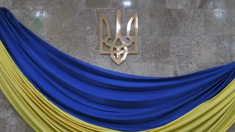 Emblem of Ukraine mounted on a stone wall with blue and yellow draped fabric Stock Footage 345682510