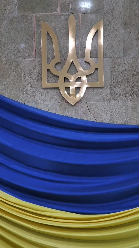 Emblem of Ukraine mounted on a stone wall with blue and yellow draped fabric Stock Footage 345682511