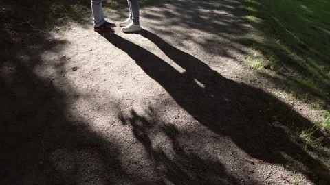 Embraced couple's feet in the background cast a long shadow of their bodies Video stock 280123150