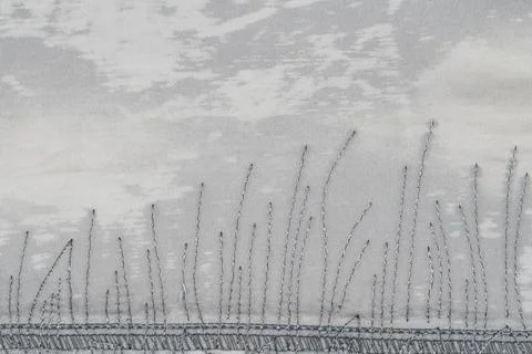 Embroidered grass pattern on textured fabric with soft gray tones 写真素材
