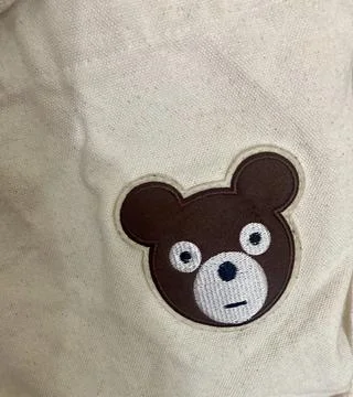 Embroidered Teddy Bear Patch on Off-White Canvas Fabric Fotos de archivo