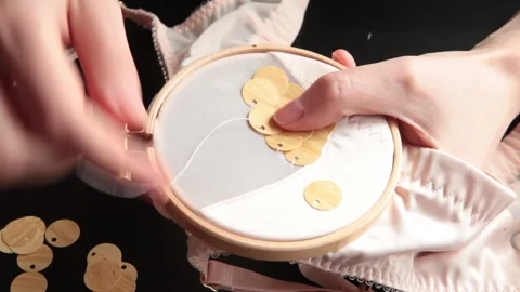 The embroiderer embroiders large beads and sequins. The fabric is hooped Stock Footage 146262867