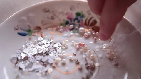 The embroiderer is stringing beads and sequins on the needle Stock Footage 146260172