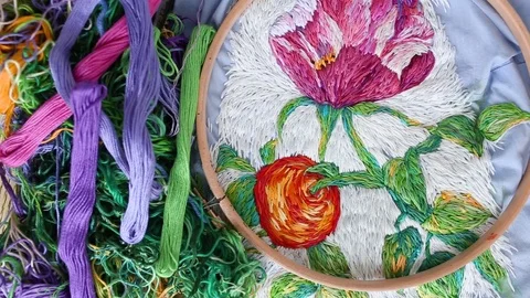 Embroidery hoops, threads, needles on embroidered fabric with colorful pattern Stock Footage 118319935