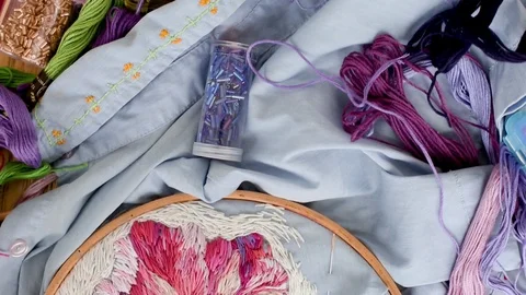 Embroidery hoops, threads, needles on embroidered fabric with colorful pattern Stock Footage 120087449