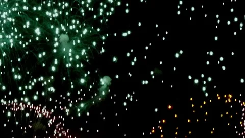 Emerald and gold fireworks explode over dark skies at New Year's Eve Video stock 320009374