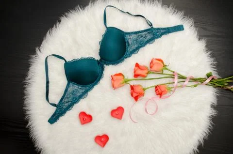 Emerald bra with lace on white fur. Orange roses, heart shaped candles. Fashi Stock-Fotos