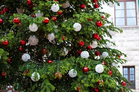 Emerald green Xmas tree with light white and red balls in the street. Medieval Stock Photos