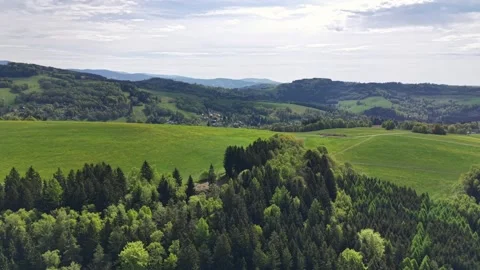 Emerald hills roll across patchwork farmland with scattered villages and forest Stock Footage 346263013