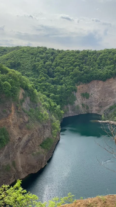 Emerald Lake in Rugged Cliffs, Green Forests, Camera Pans Right, Cloudy Sky Stock Footage 339480180