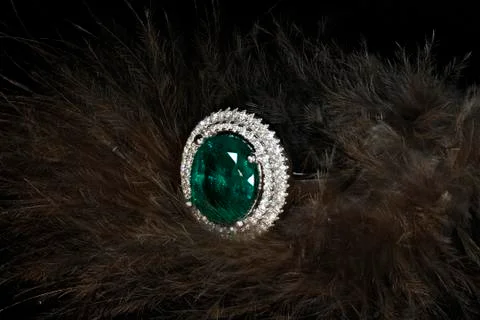 Emerald ring with diamonds on feathers background Stock Photos