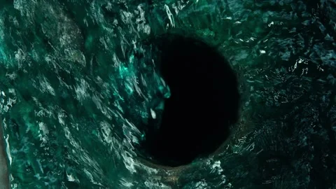 Emerald water spirals into a vortex, disappearing into a drain. Video stock 301390200