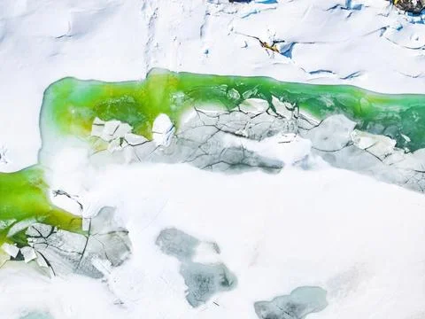 Emerald water through melting ice at Lake Pirola Foto stock