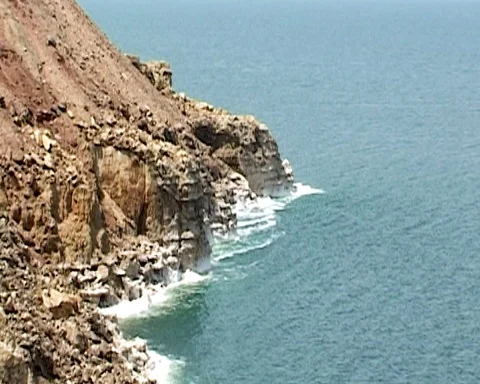 Emerald waves splash against stones with salt crystals. Dead Sea in Jordan. Stock Footage 114413218