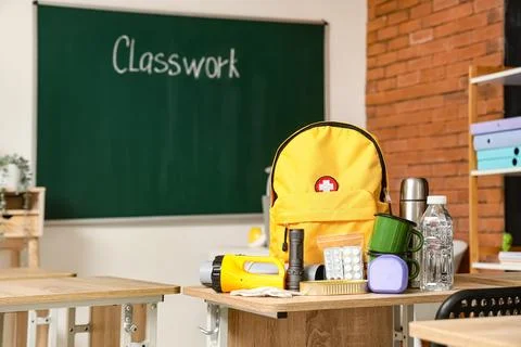 Emergency backpack and necessities on table in empty classroom Stock Photos