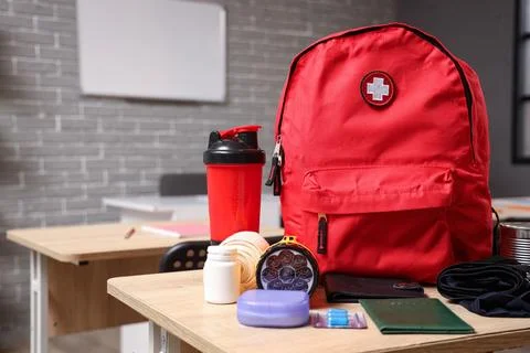 Emergency backpack with necessities on desk in classroom Stock Photos