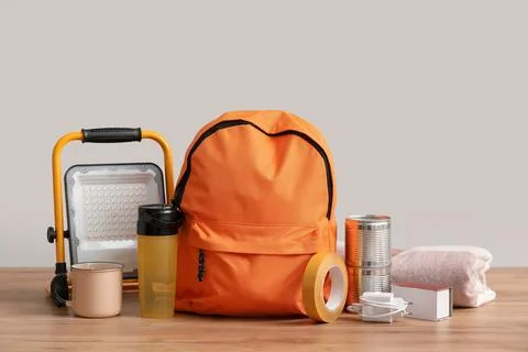 Emergency backpack with necessities on table near light wall Stock Photos