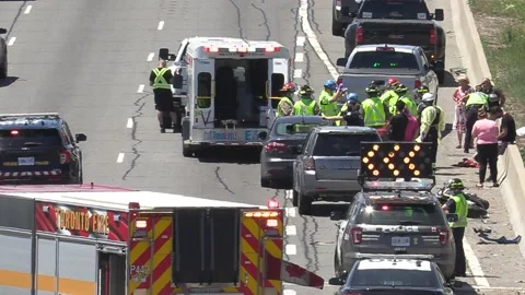 Emergency crews at accident scene with motorcycle on busy highway Stock Footage 155576822