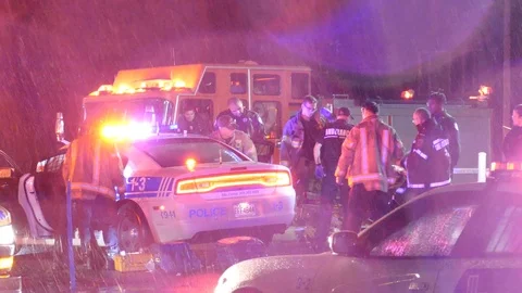 Emergency crews surround cop car after shooting in soaked rainy night Stock Footage 99011509