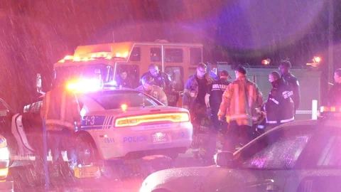Emergency crews surround cop car after shooting in soaked rainy night - 24fps Stock Footage 104048599