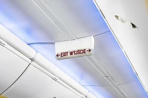 Emergency exit sign and direction indicator on an airplane Stock Photos