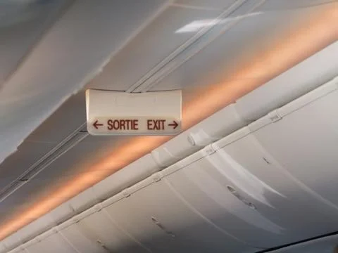 Emergency exit sign on the ceiling of airplane Stock Photos